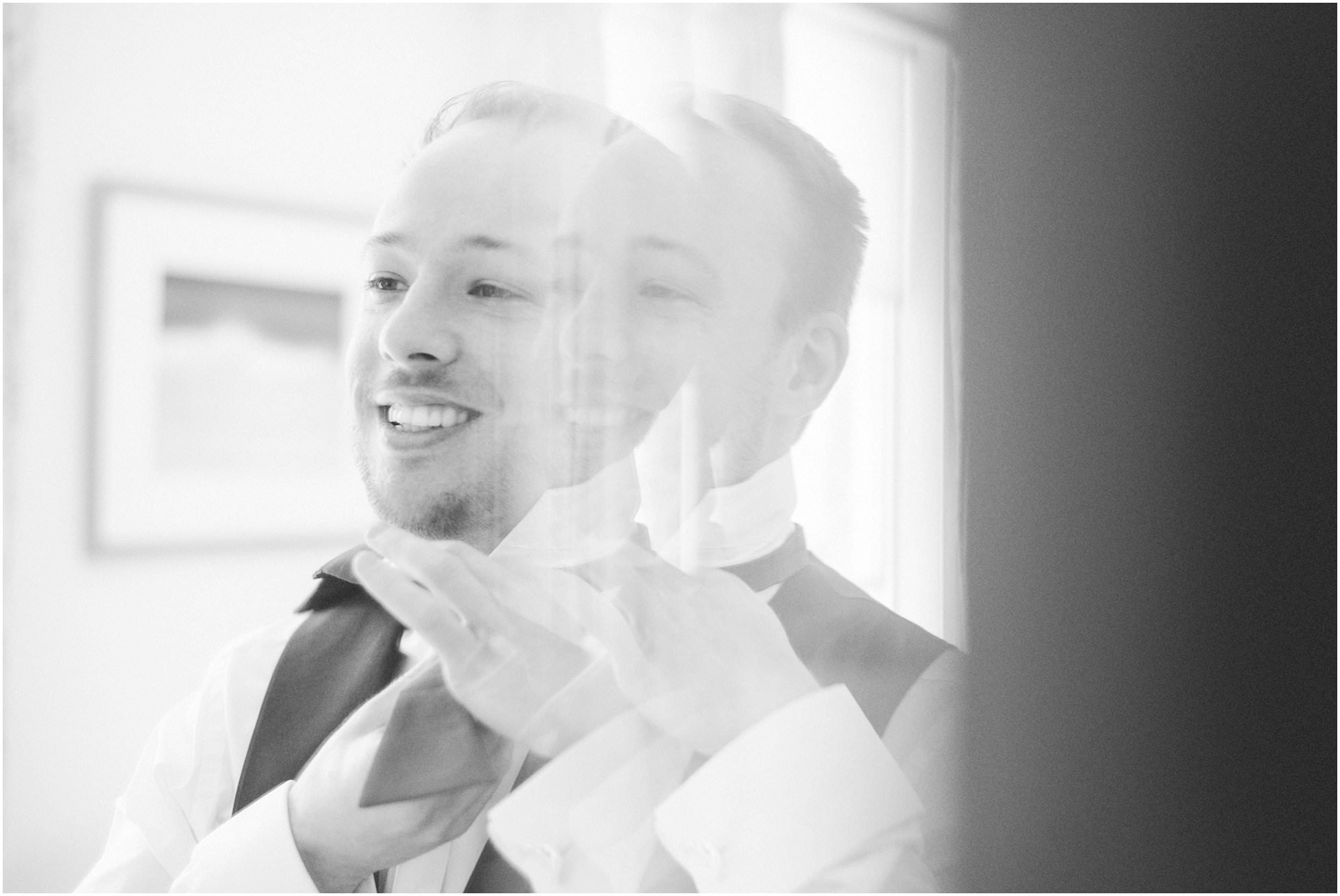 Groom getting ready through the mirror
