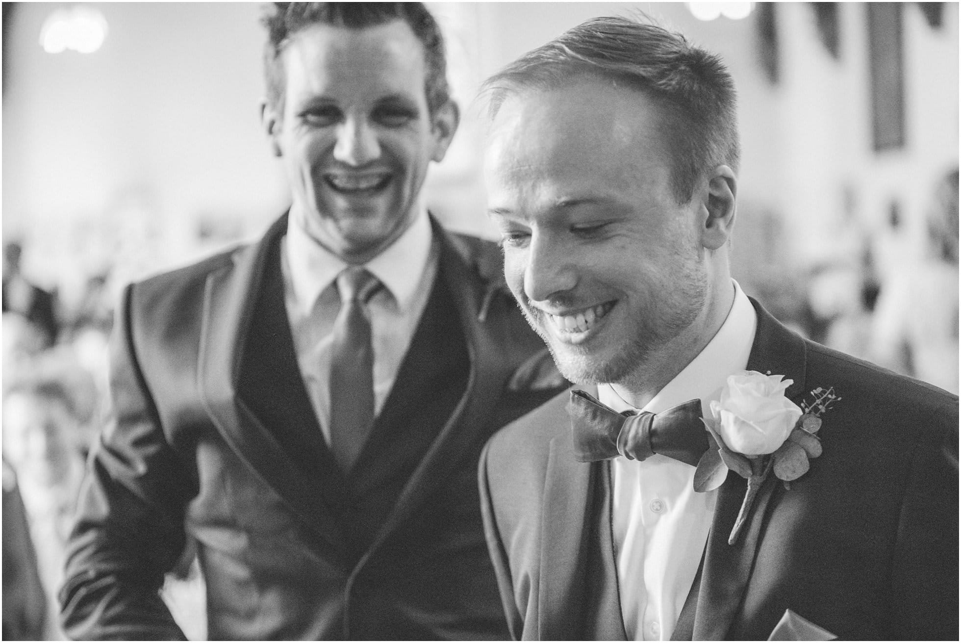 Unobtrusive wedding photography shot of groom and bestman