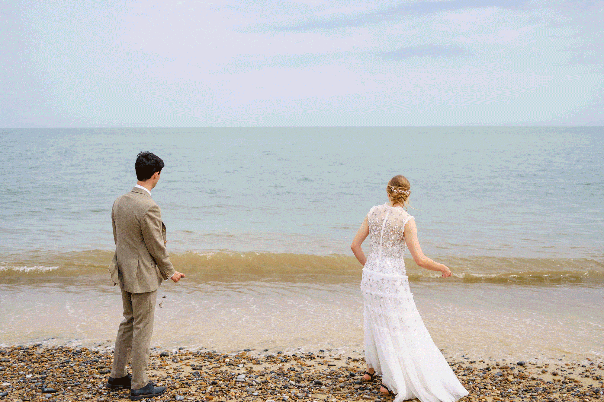Wedding couple skimming stones on a beach