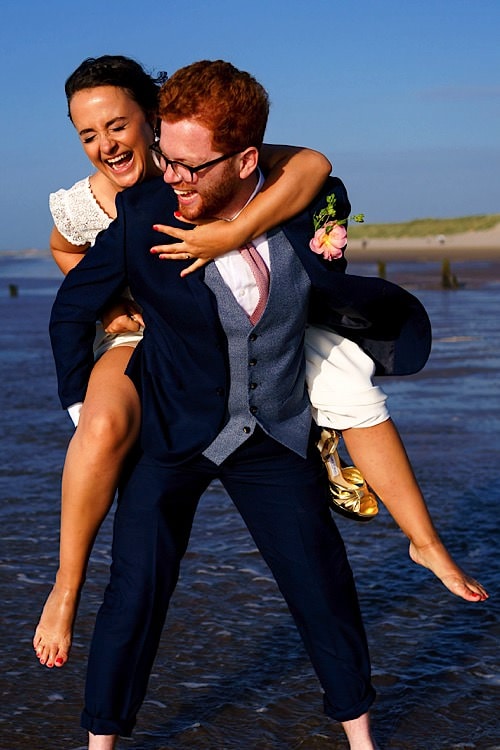 Groom carrying bride on a Norfolk beach