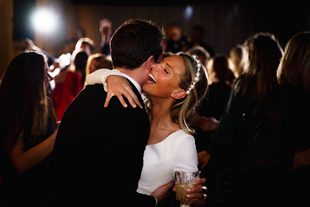 Bride smiling big whilst dancing with her groom
