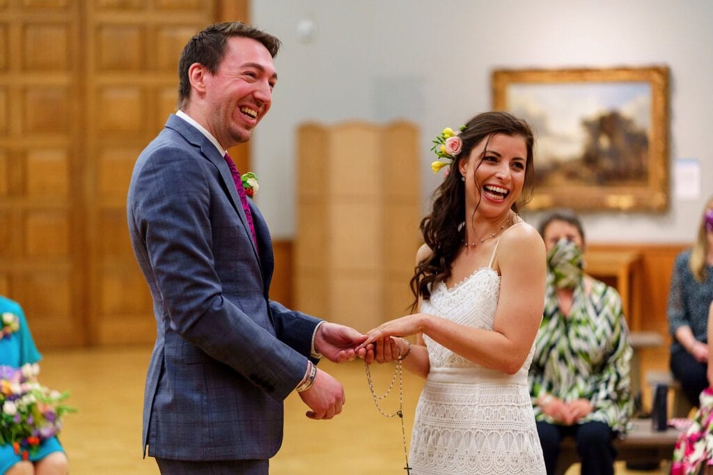 Bride and groom smiling as they exchange rings at Norwich Castle