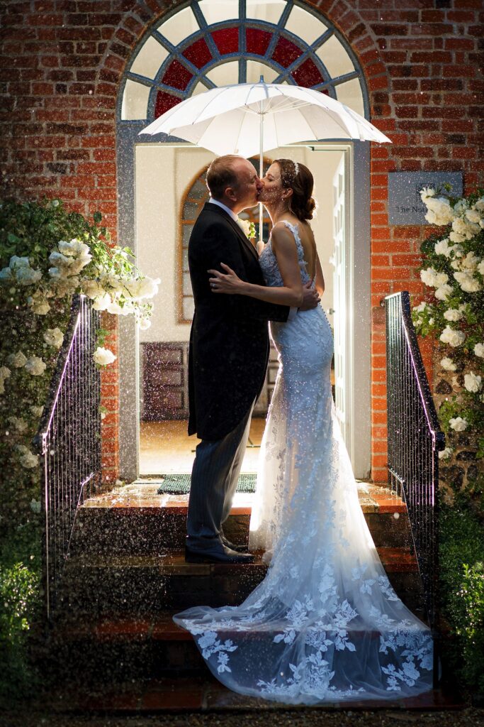 Bride and groom kissing in the rain