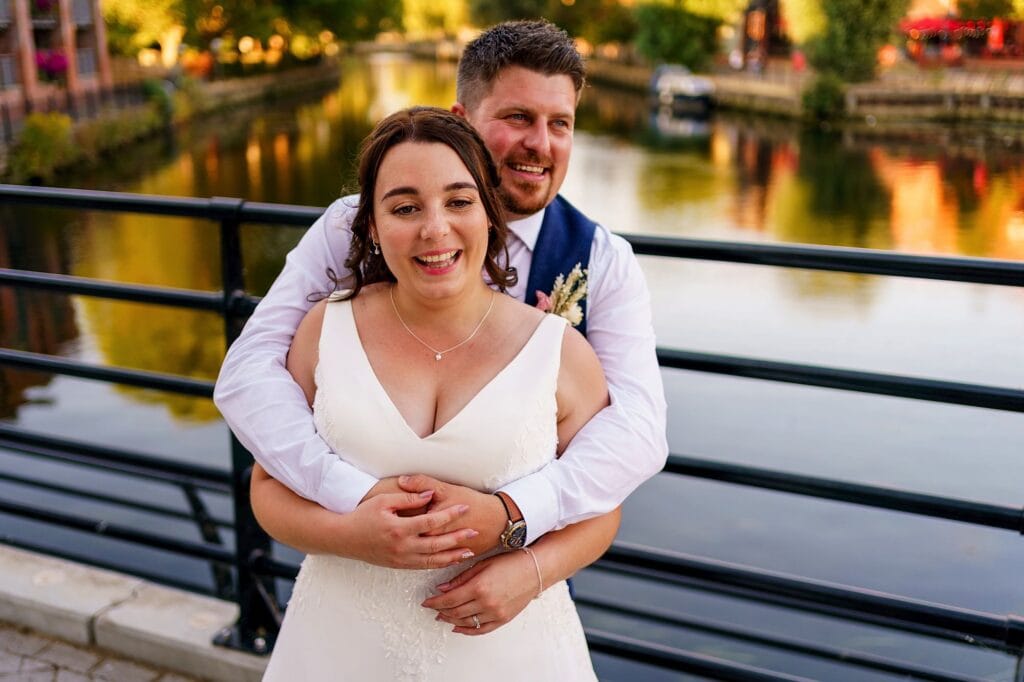groom hugging bride from behind by the River Wensum