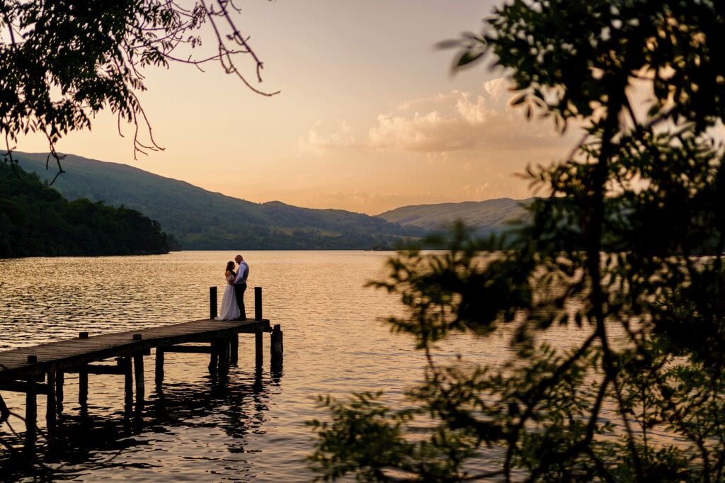 Wedding couple on jetty over lake at sunset