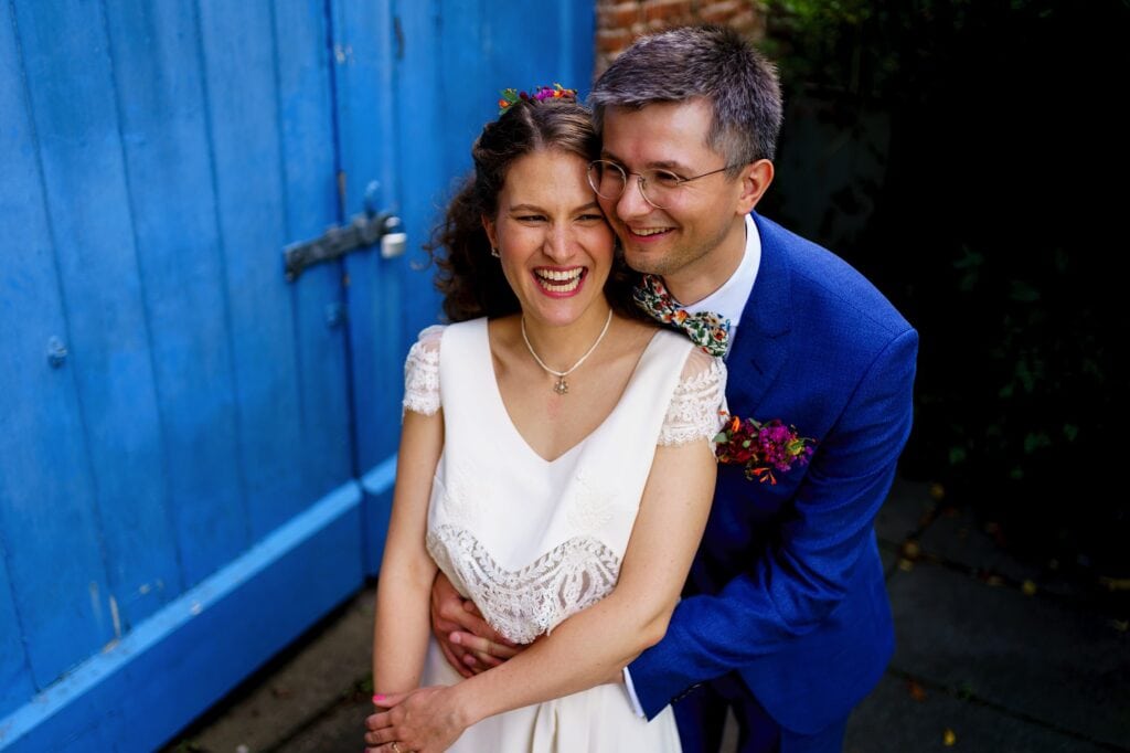 Laughing bride being hugged from behind by groom in blue suit
