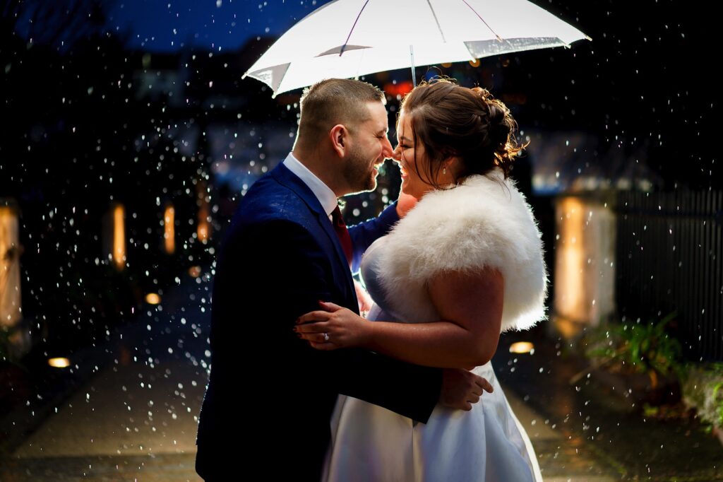 Couple laughing under an umbrella at night