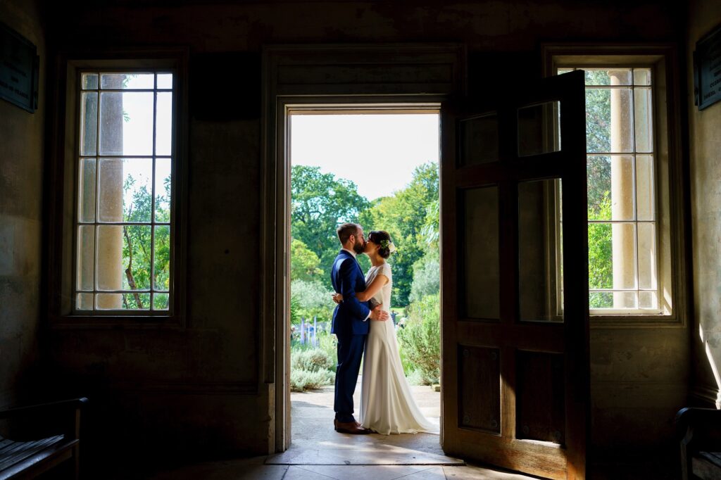 Bride and groom kissing through a doorway