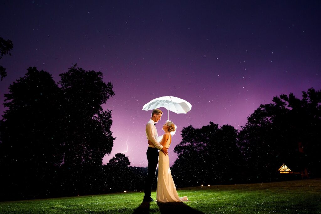 Beautiful wedding photo of couple under an umbrella, starry, purple sky and lightning bolt