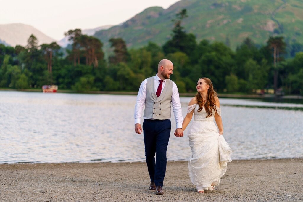 Wedding couple walking away from a lake hand-in-hand