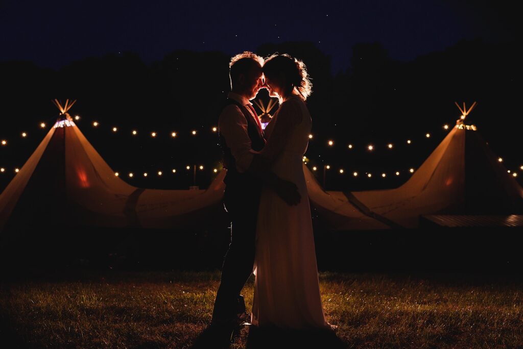 Bride and groom in front of marquee at night