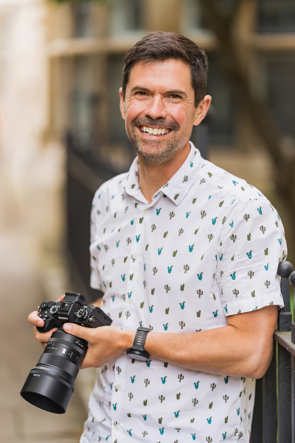 Portrait of a male photographer holding a Sony camera outdoors, smiling at Winston Sanders Photography.