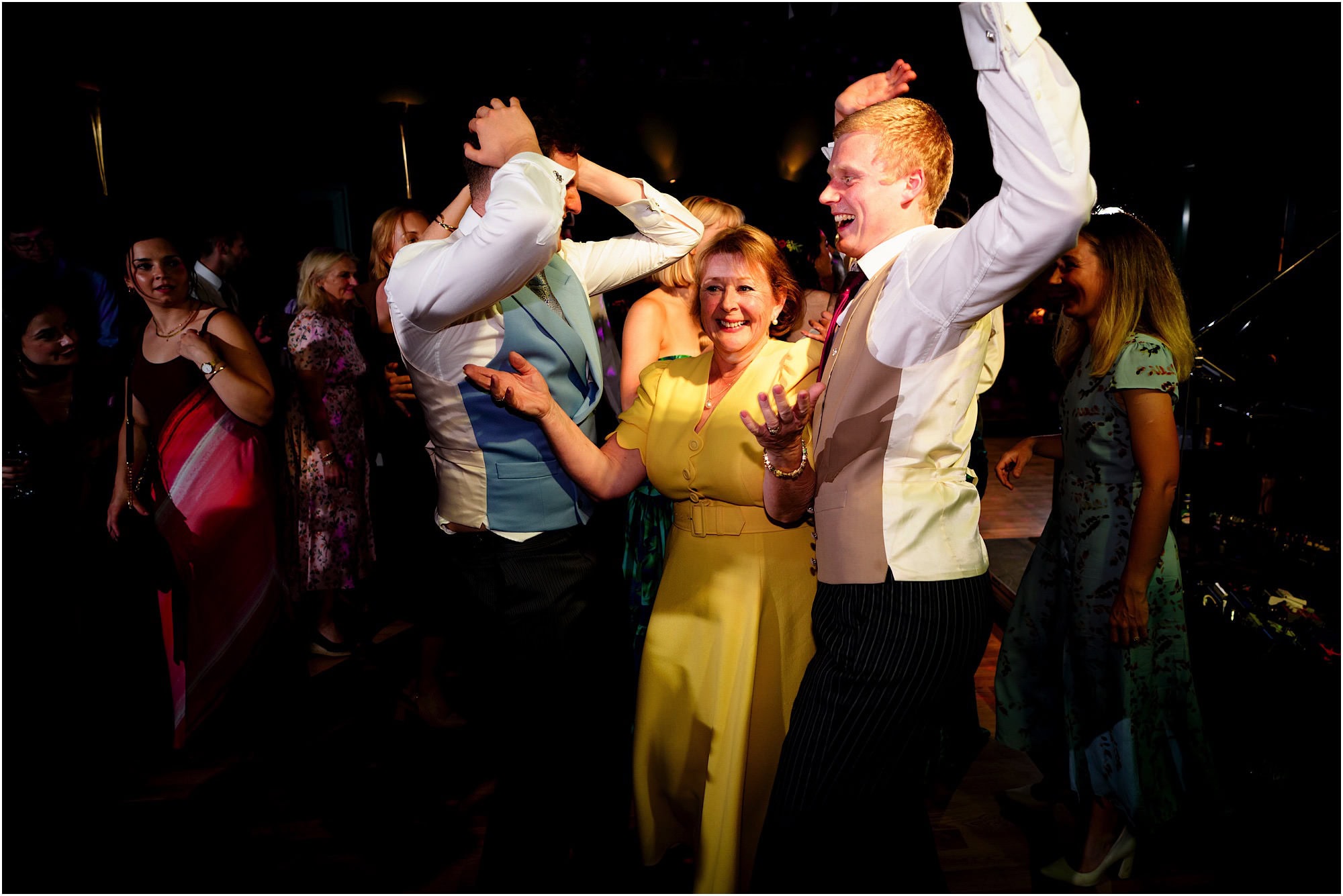 Happy guests dancing and celebrating at a wedding reception in a lively atmosphere.