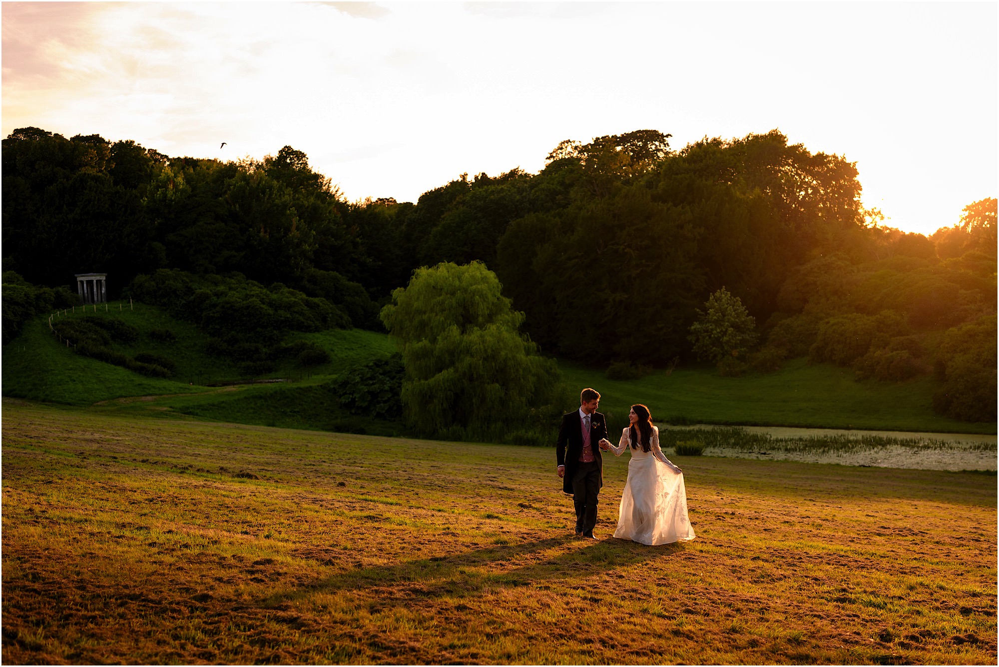 Romantic wedding photography of a couple walking hand in hand at Birdsall House during sunset.