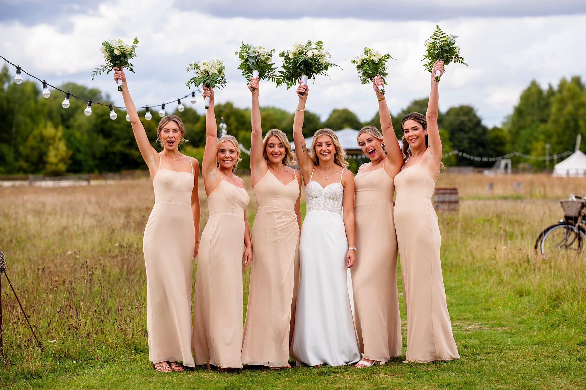 bridesmaids cheer with flowers at Wellington Wood
